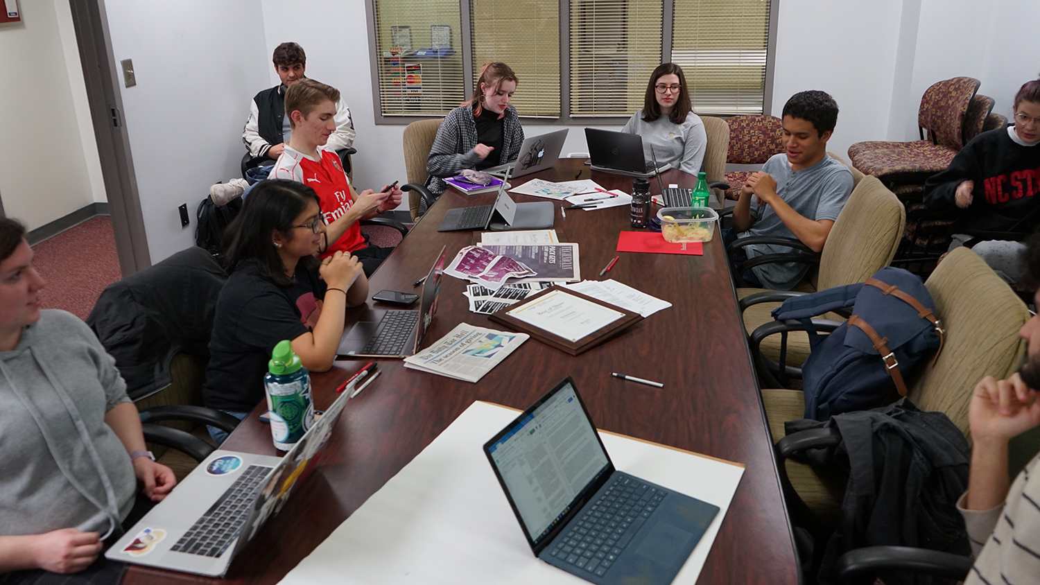 Technician staffers gathered around a table for an editorial meeting