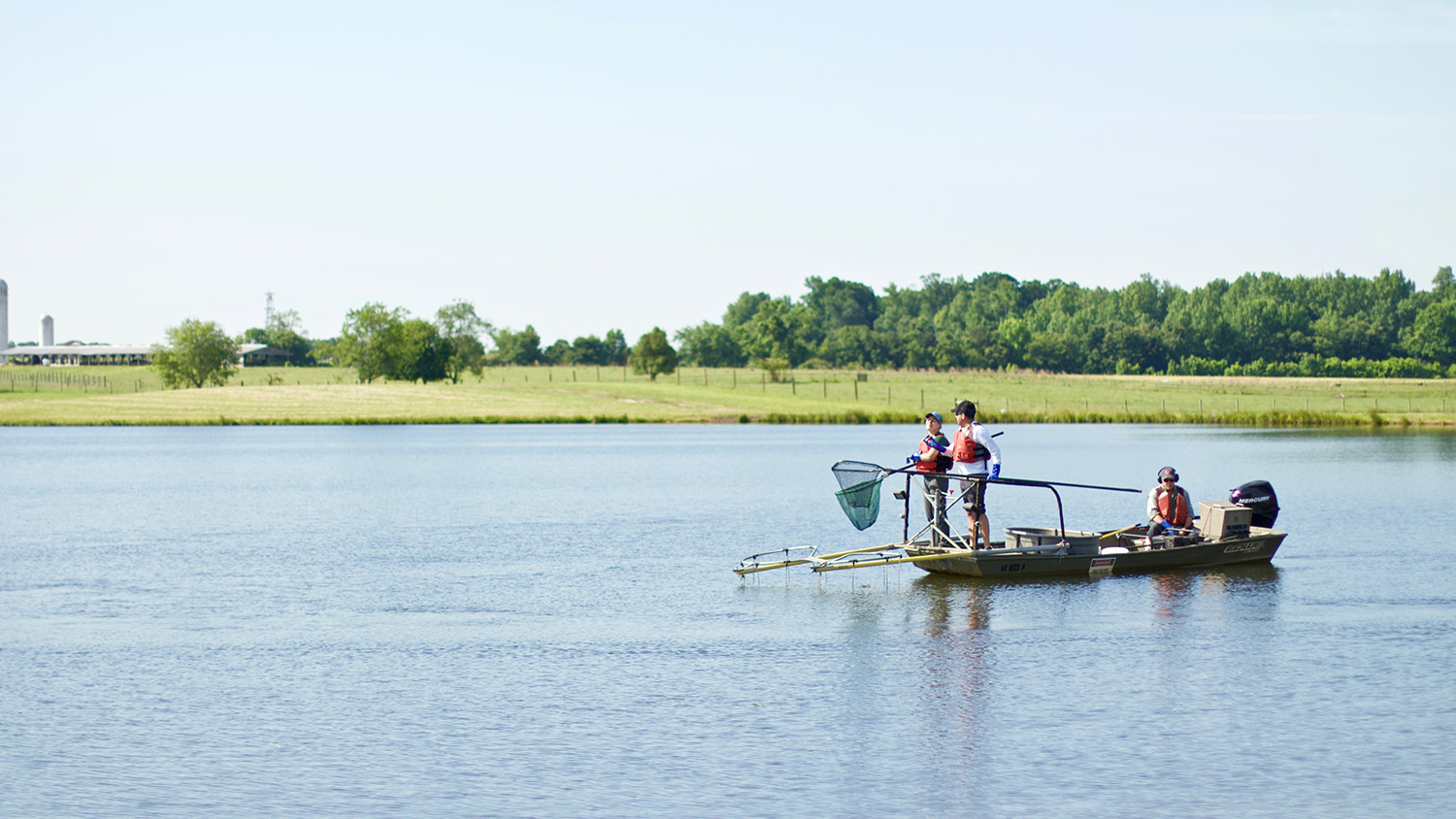 three scientists with an electrofisher mounted on a small boat