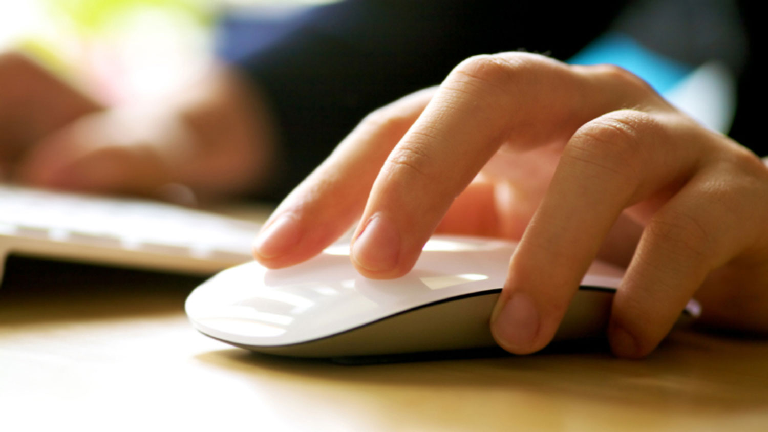 image of a hand on a wireless mouse with a keypad in the background