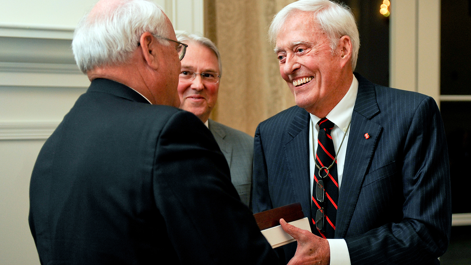 Bob Jordan shakes hand of another trustee with Chancellor Woodson looking on.