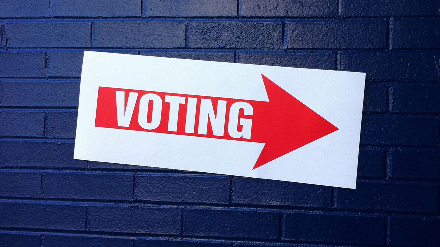 voting sign on a brick wall