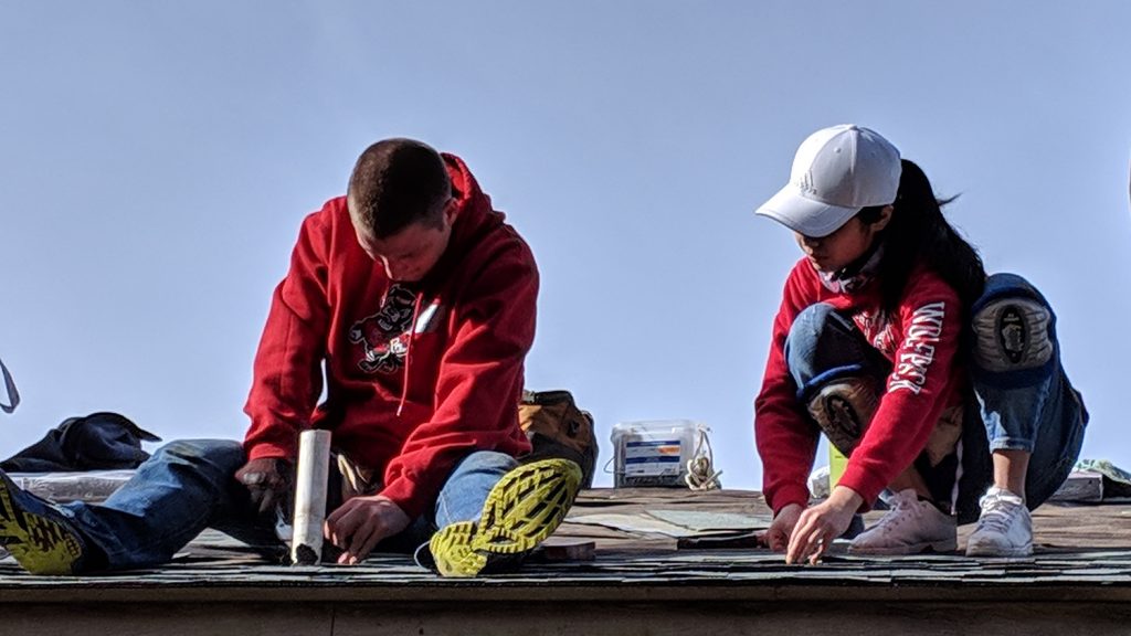 Two people work on top of a roof