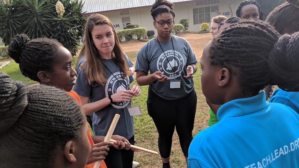 Two NC State students gather outdoors with a group of young students in Rwanda