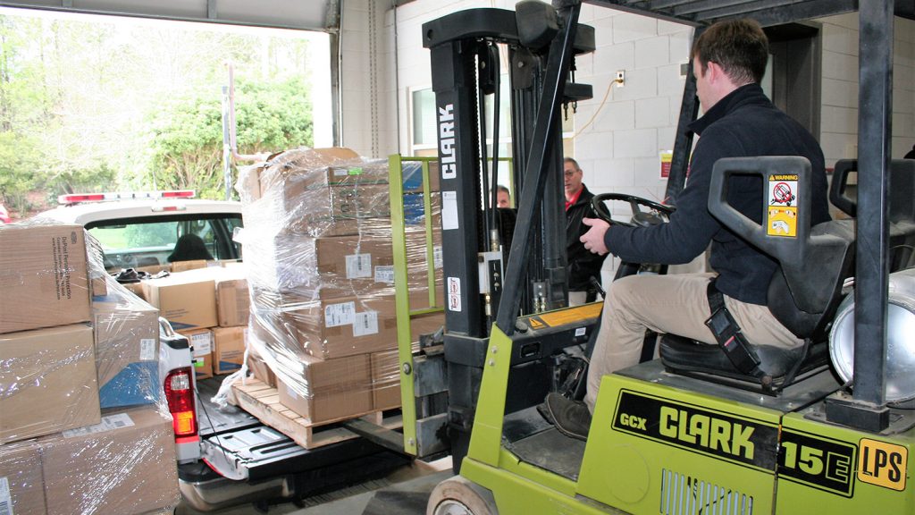 Forklift loading boxes into a truck at a loading dock.