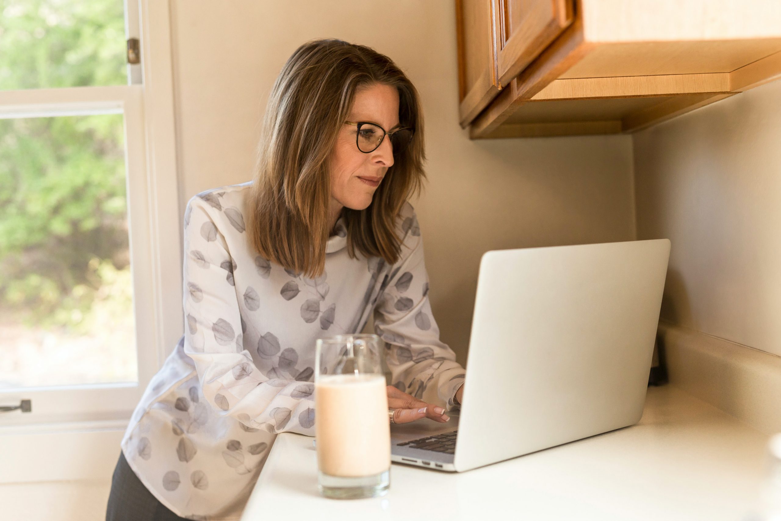 Woman in a kitchen using a laptop computer on a counter