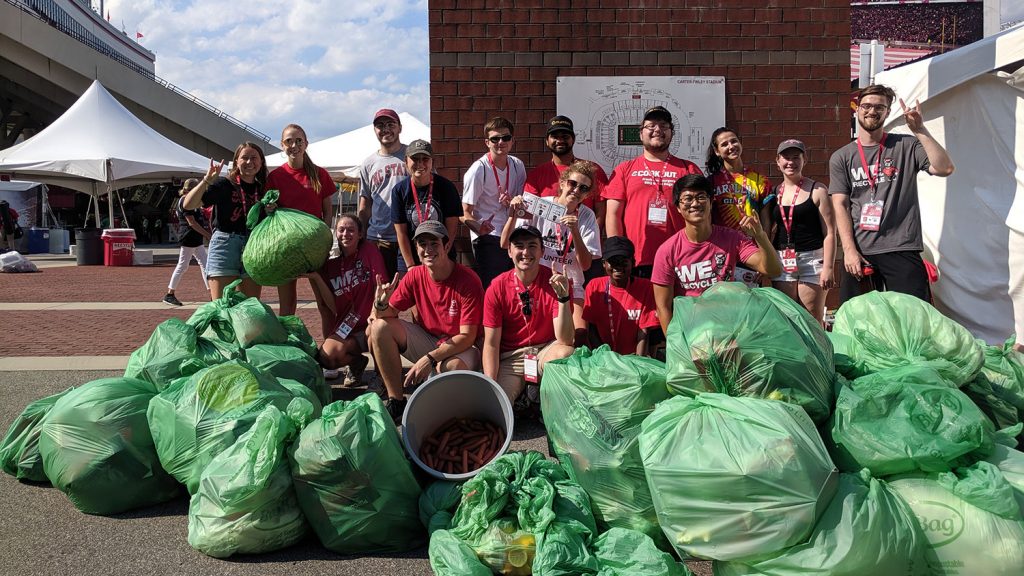 group of people standing with green bags full of compost