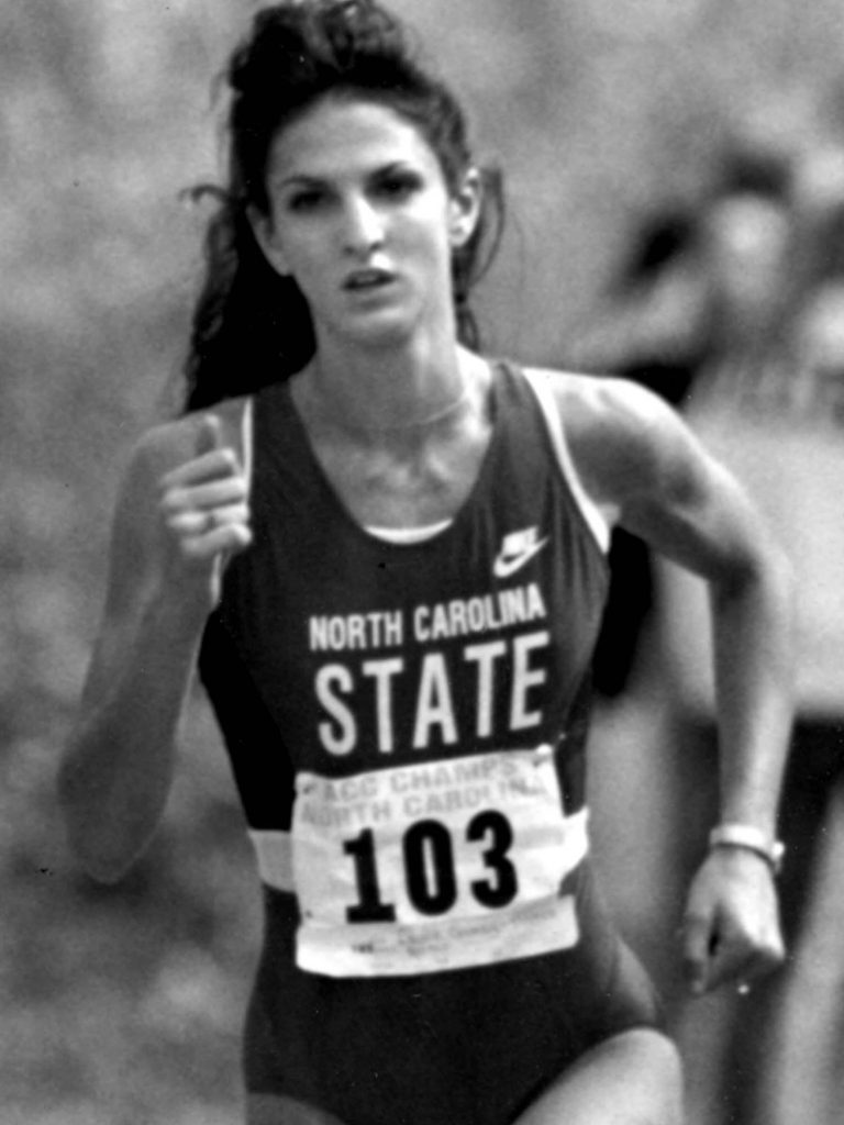 Laurie Henes wearing an NC State jersey and running in the cross country NCAA Championship in 1991