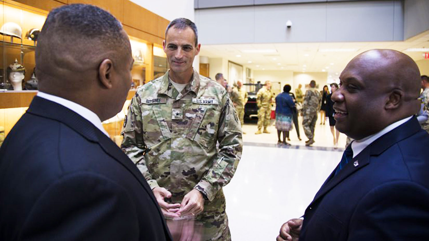 man in National Guard uniform talking with two other men