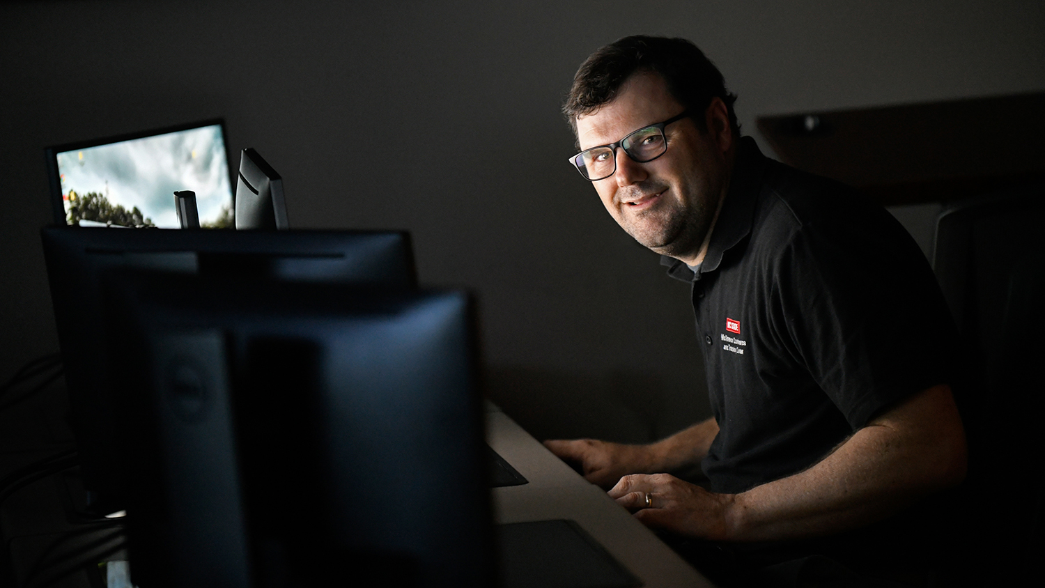 Rob Chapman sitting in front of a computer screen with the light reflecting onto his face.