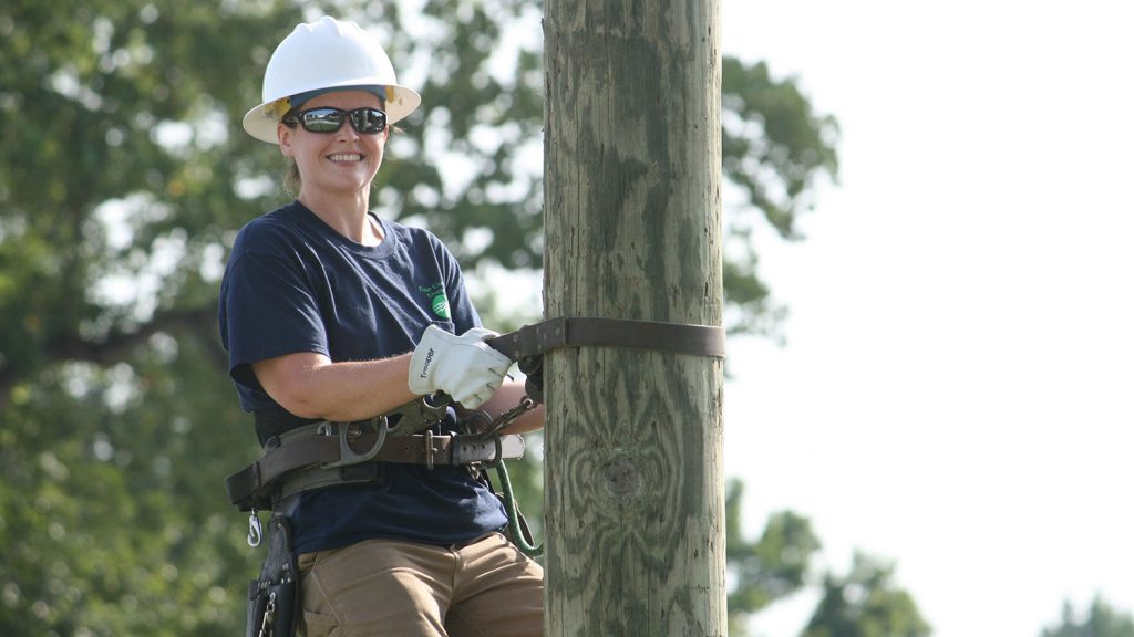 woman in hard hat on electrical pole