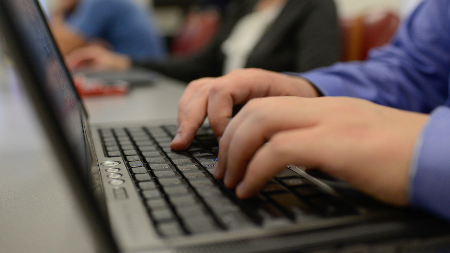 Hands on a laptop keyboard.