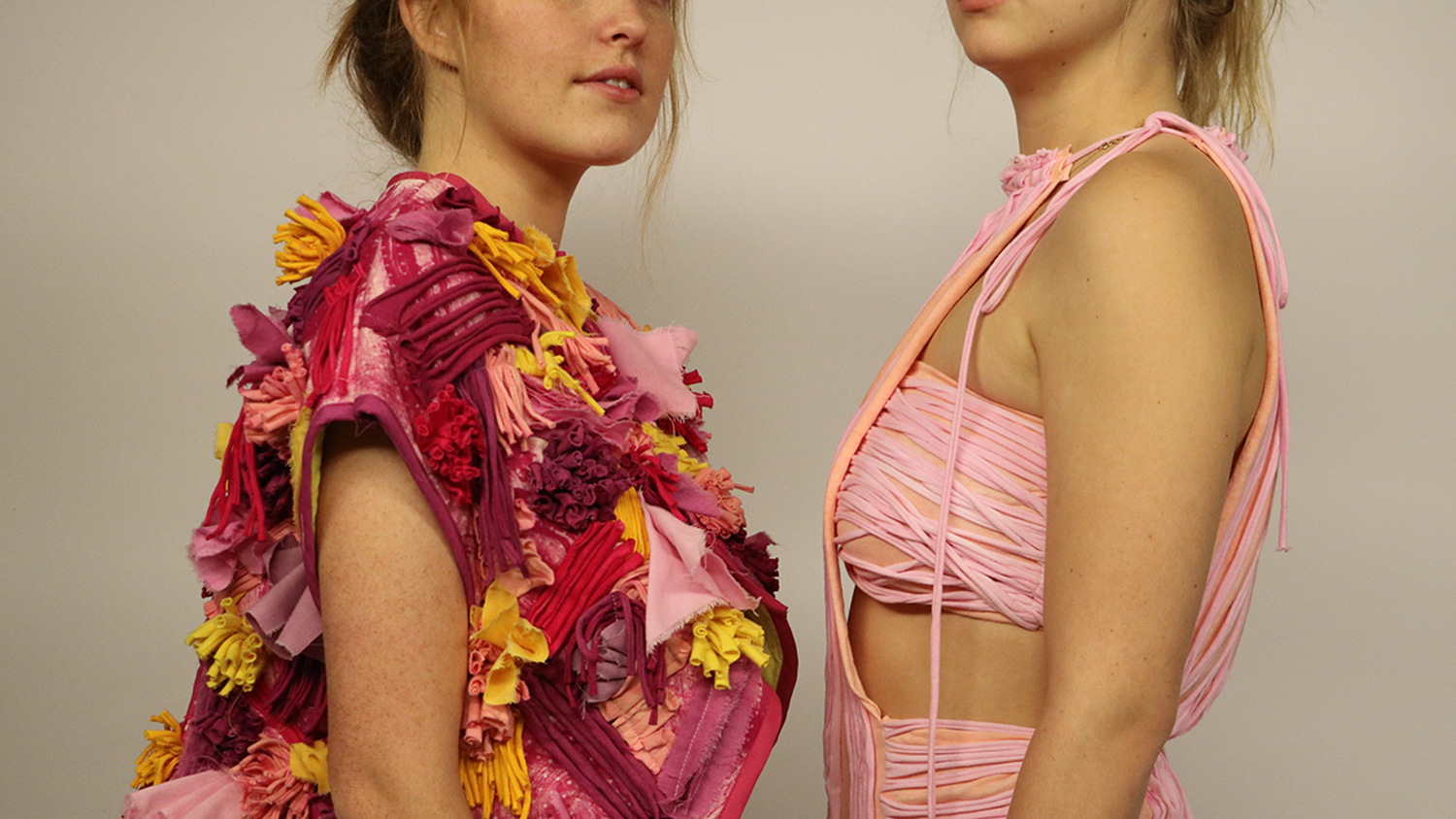 Two students model pink, textural garments as part of an Art2Wear collection.