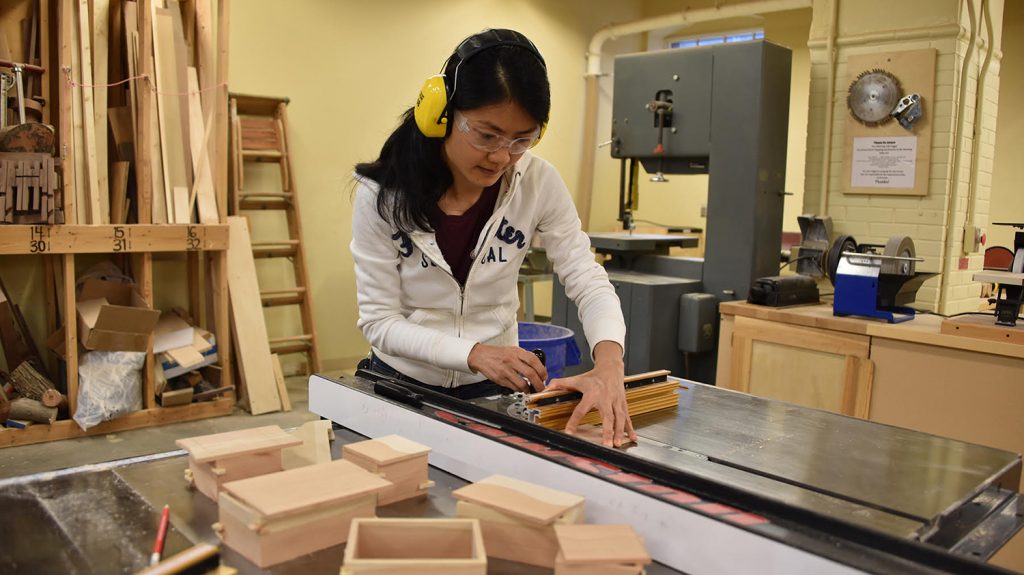 A woman uses a table saw for woodworking.