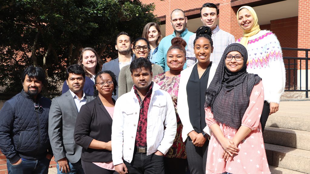 Erika Ford and students stand outside of a brick building on campus.