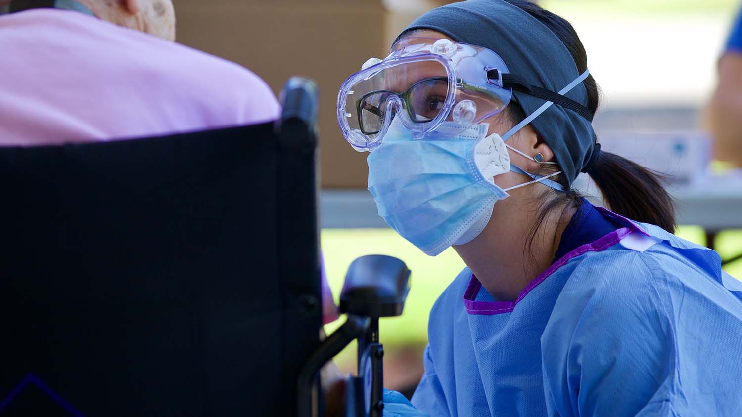 masked healthcare worker talks to elderly patient