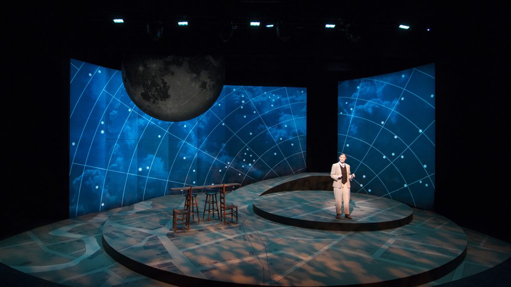 A man stands on stage under starry lights.