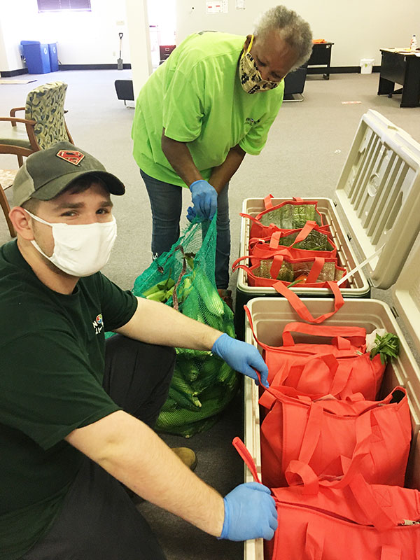 A man and a woman adding corn to produce bags in coolers. 