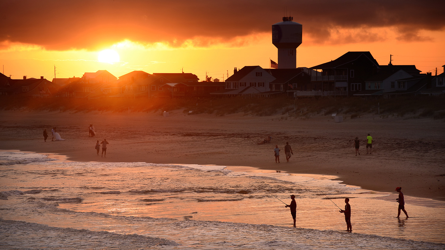 Surf fishermen fish along the waves of Atlantic Beach during the last few minutes of daylight.