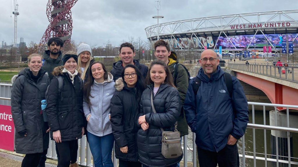 Professor and students pose in front of London Stadium.