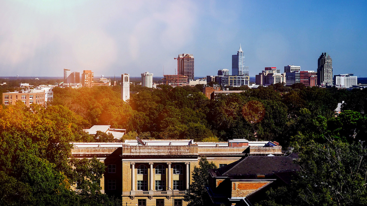 Ricks Hall (in the foreground) and the Belltower on NC State's campus, with downtown Raleigh behind.