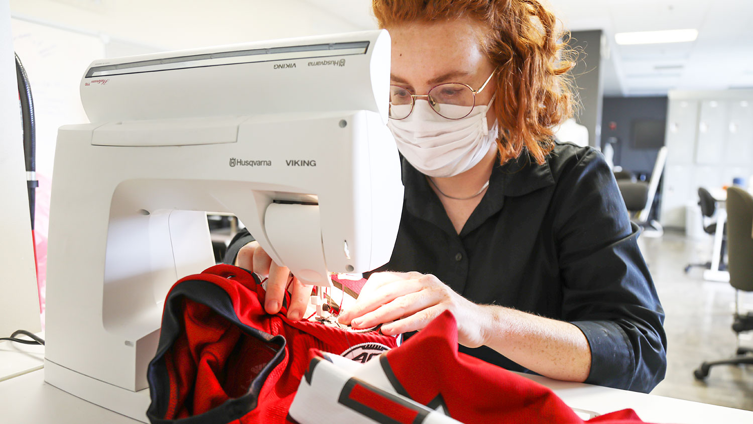 Bailey Knight sews patches onto the Wolfpack football team's uniforms