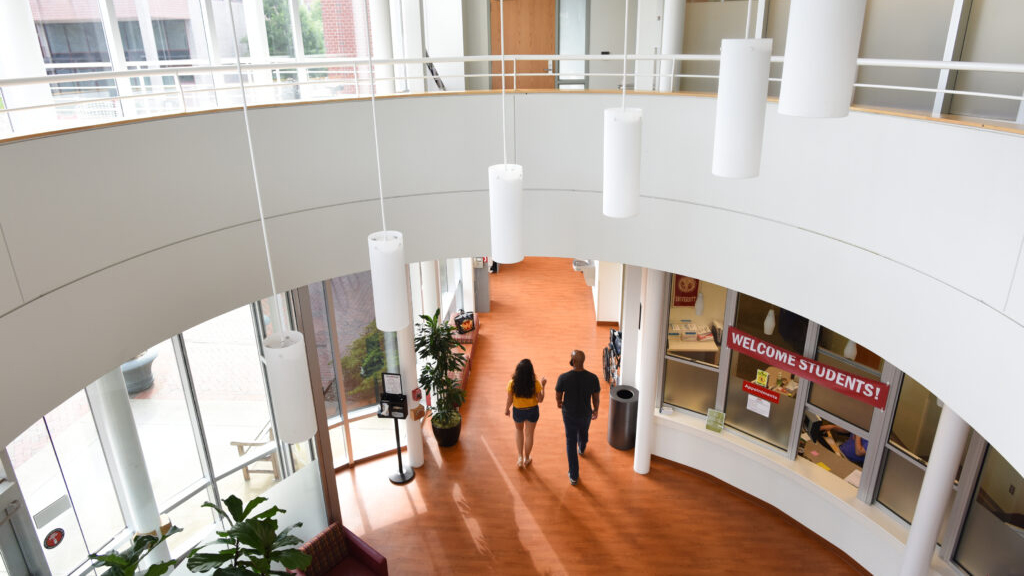 Two people walk through the open spaces within the NC State Student Health Services building.