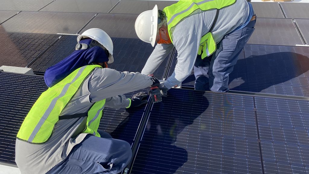 Workers place solar panel in place.