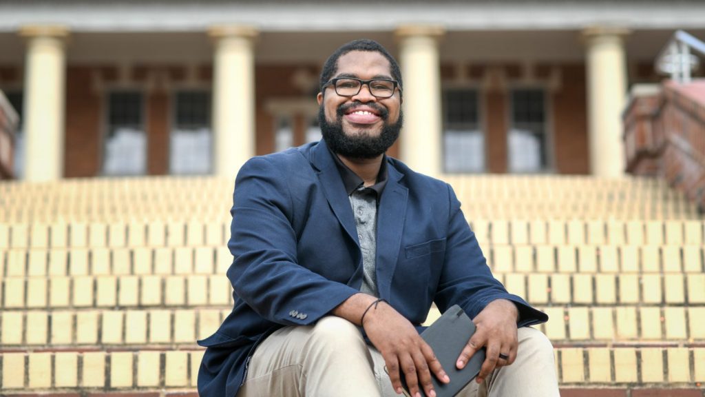 A photo of poet Tyree Daye sitting on the steps