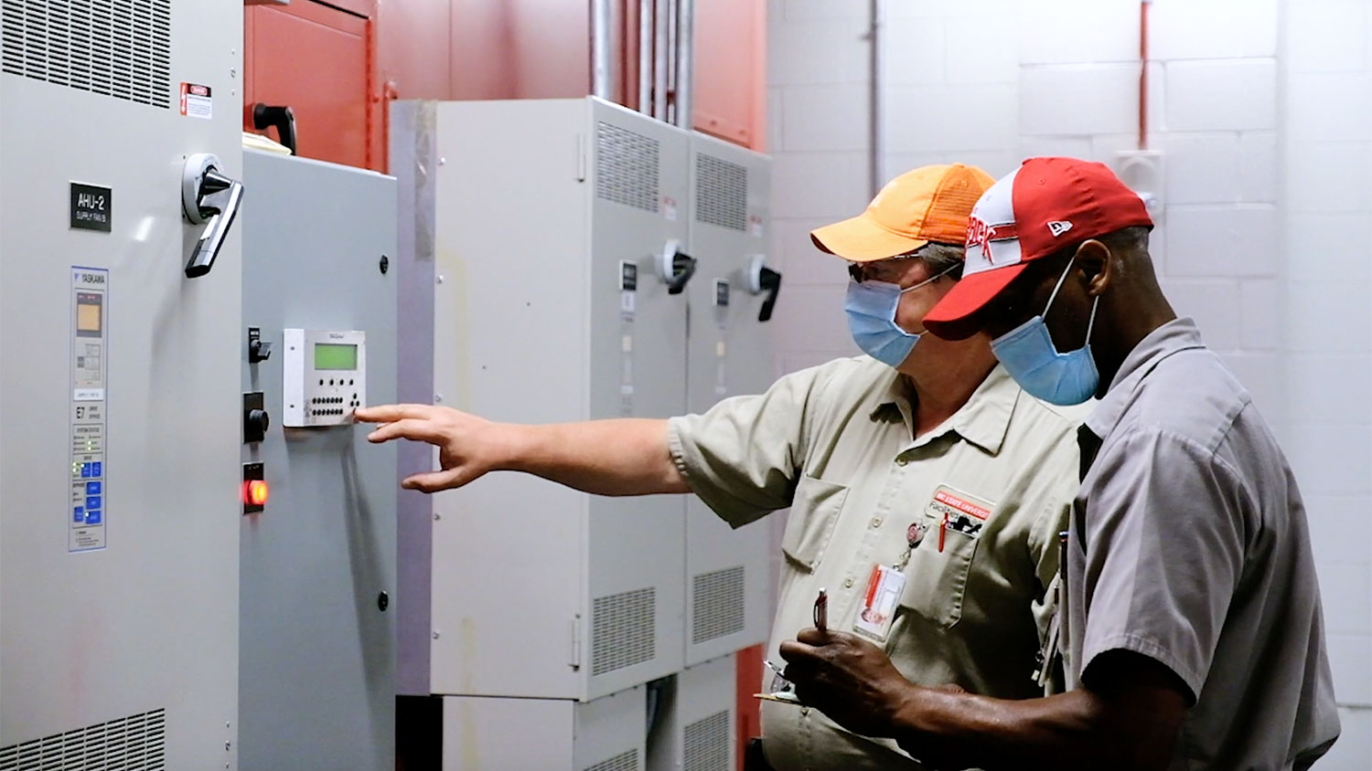 Two Facilities Division employees check the control panel of an HVAC system on campus