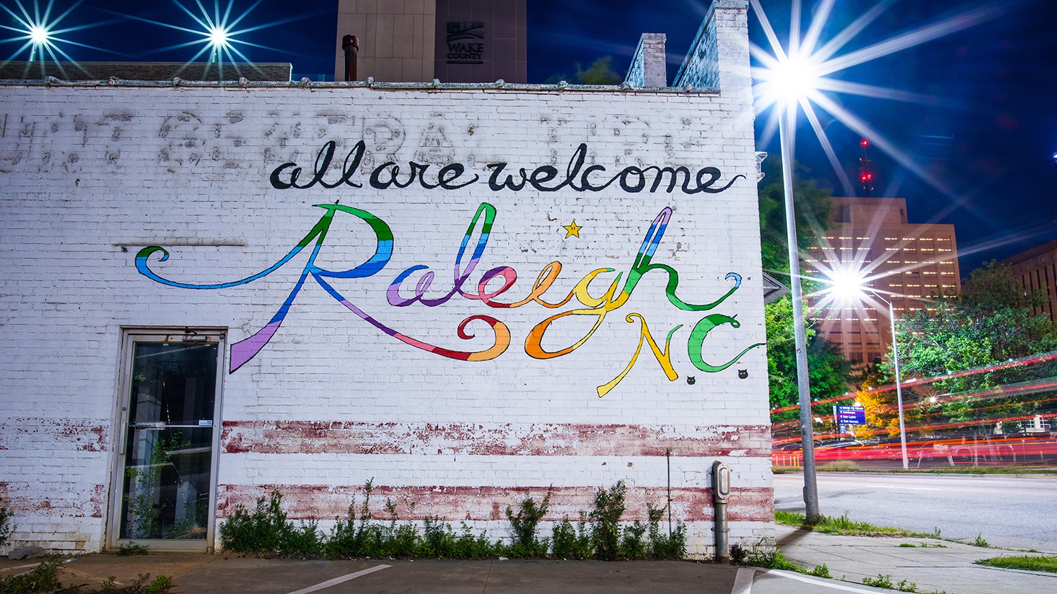 A colorful mural in downtown reads "All are welcome. Raleigh N.C."
