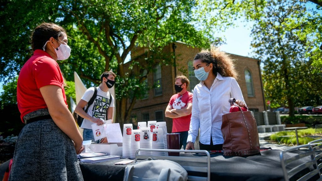 Naomi Libraty speaks with International Programs Specialist Becky Cibulskis outside at a table in the Global Courtyard on campus.