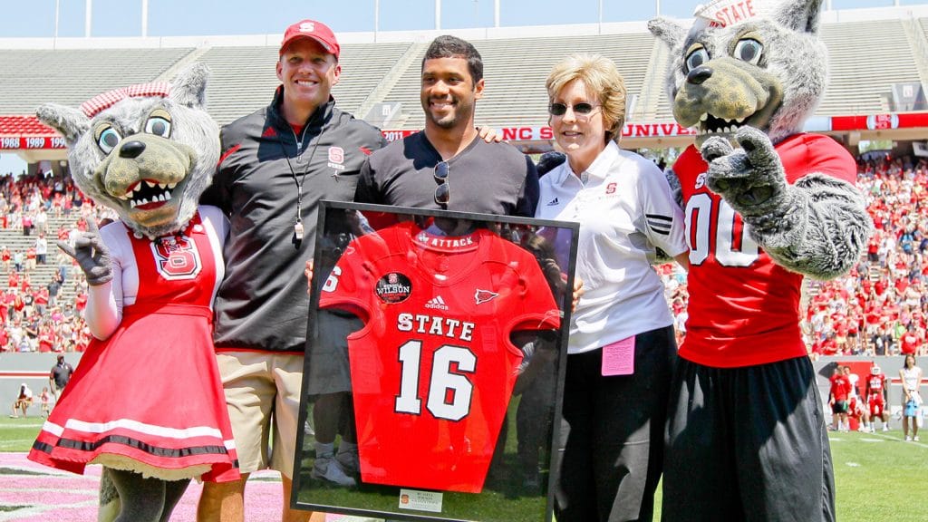 Wilson, center, at a ceremony honoring his jersey at the 2014 Kay Yow Spring Game. Wilson is flanked by Mr. and Ms. Wuf, football head coach Dave Doeren and former athletics director Debbie Yow.