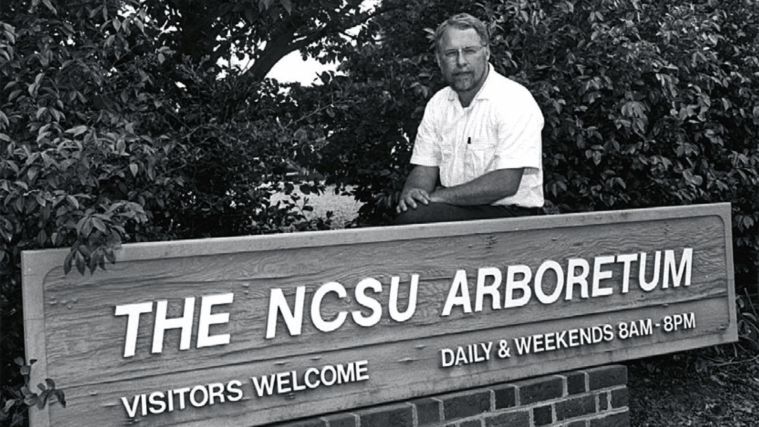 J.C. Raulston behind a sign identifying the NCSU Arboretum in the 1970s.