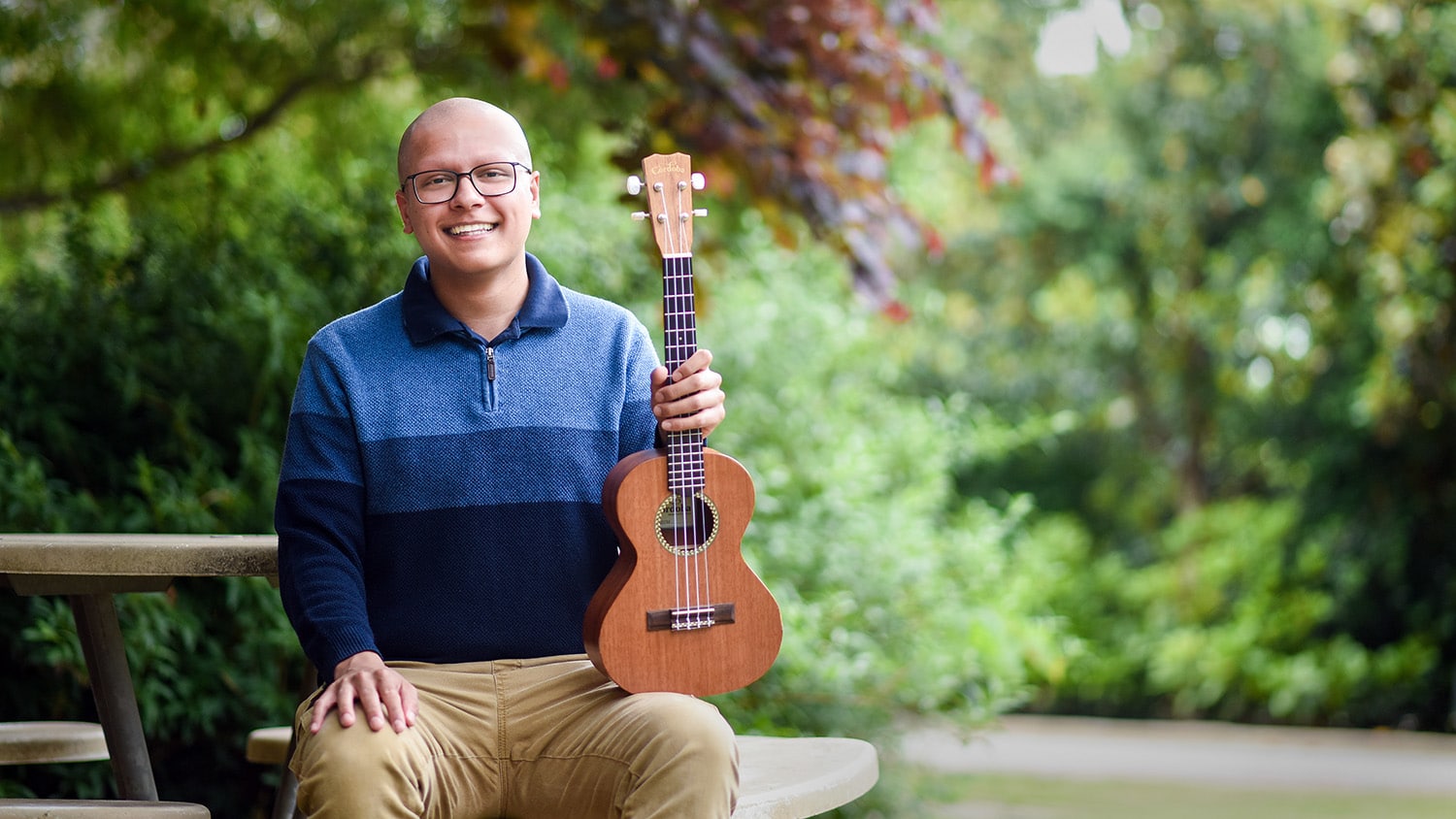 Nikhil Milind sitting outside, holding his ukulele.