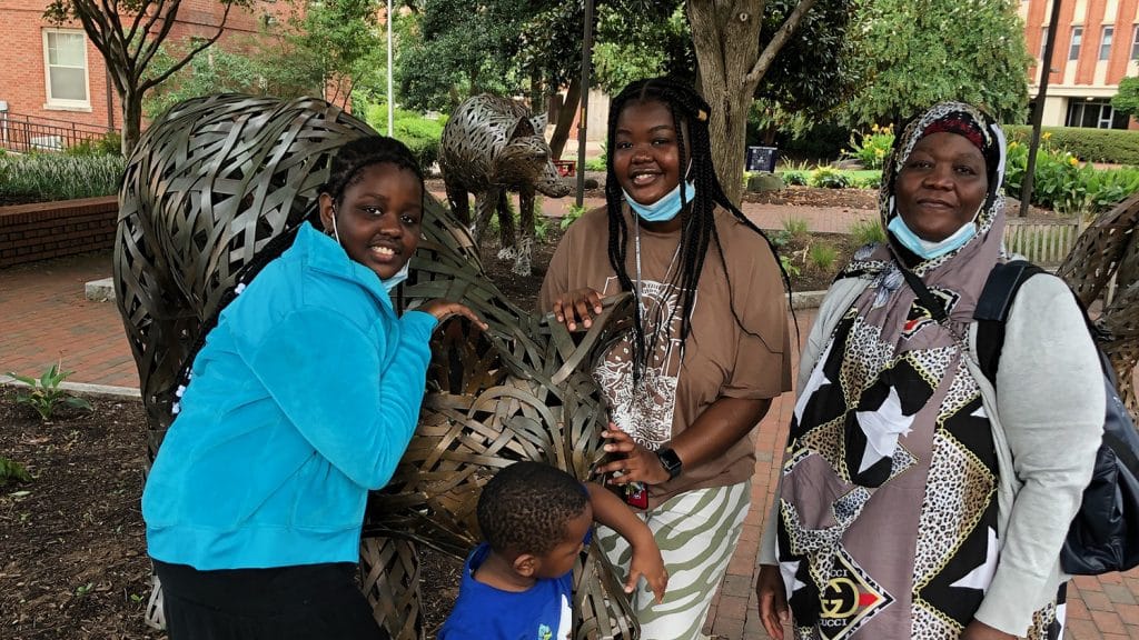 Faduma Osman with her sister, brother and mother at the copper wolf statues on campus