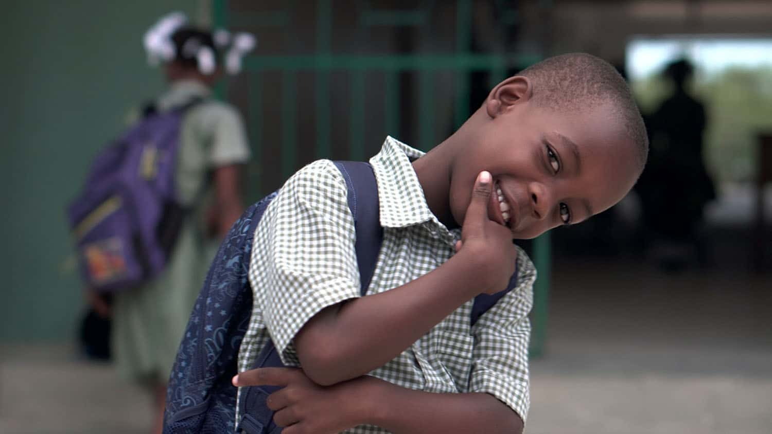 black child in a school uniform smiles at the camera