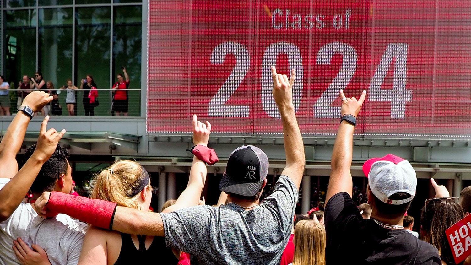 Incoming NC State students make wolf ears gestures in front of a screen reading class of 2024.