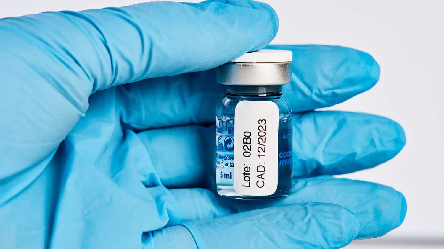 hand in a latex gloves holds a vial of covid-19 vaccine