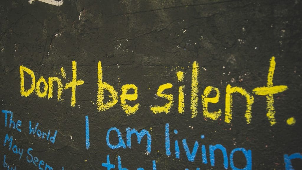 A wall in the free speech tunnel painted with phrases including "Don't stay silent" and "I live"