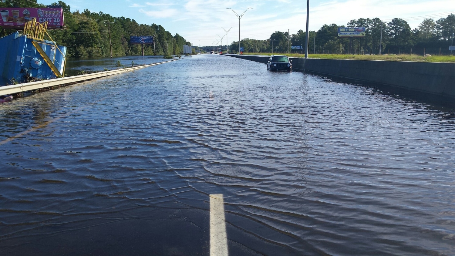 a two-lane road disappears into floodwaters