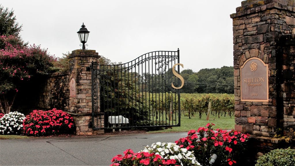 The vineyards front gates with flowers blooming in beds on either side of the entrance.