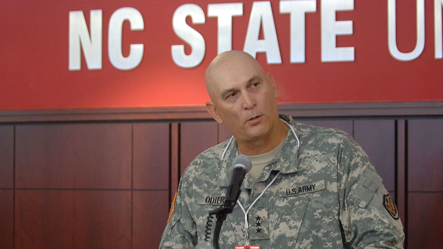 Ray Odierno seated with large sign behind him reading NC State.