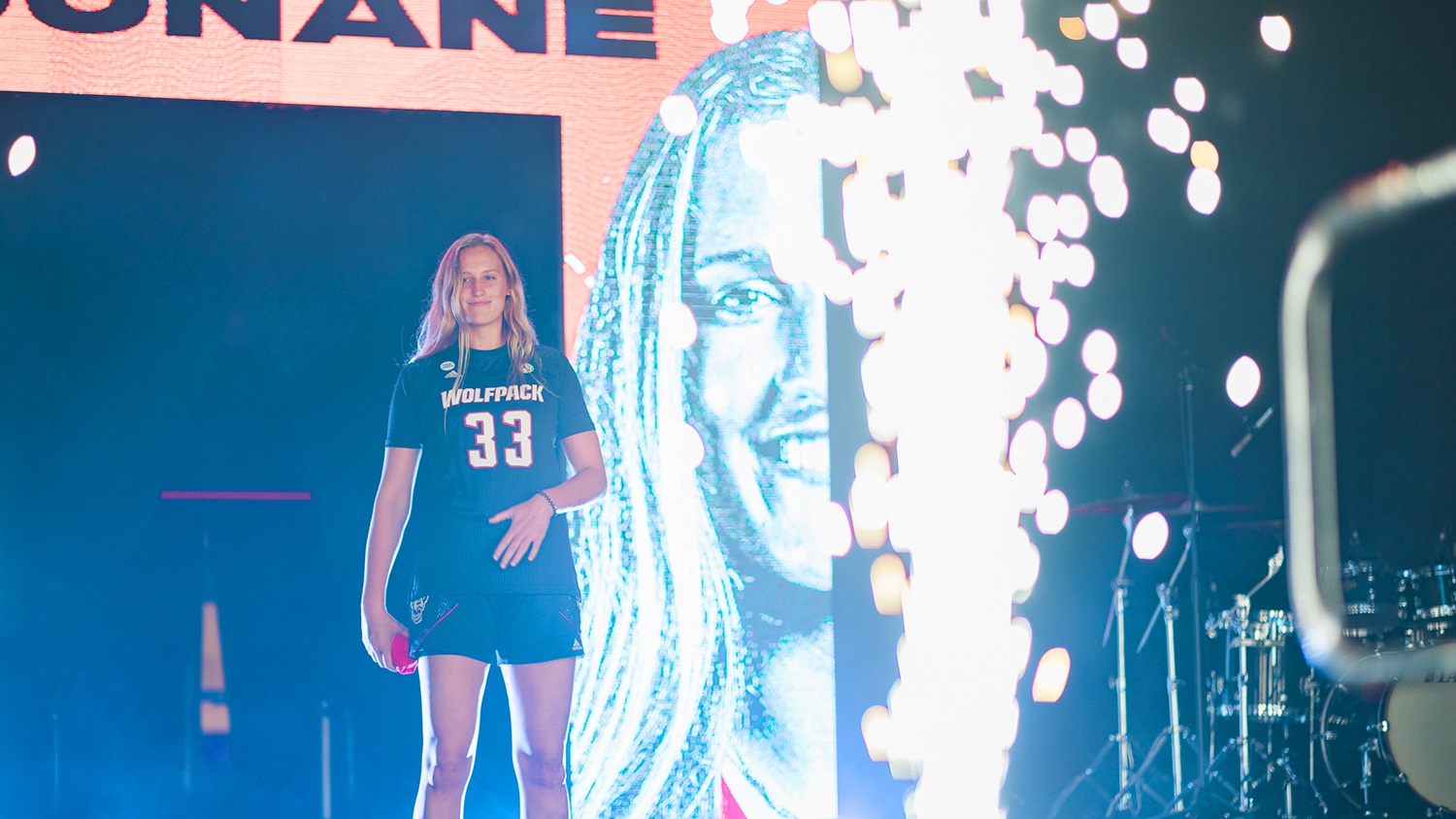 A women's basketball team player stands in front of a crowd.  