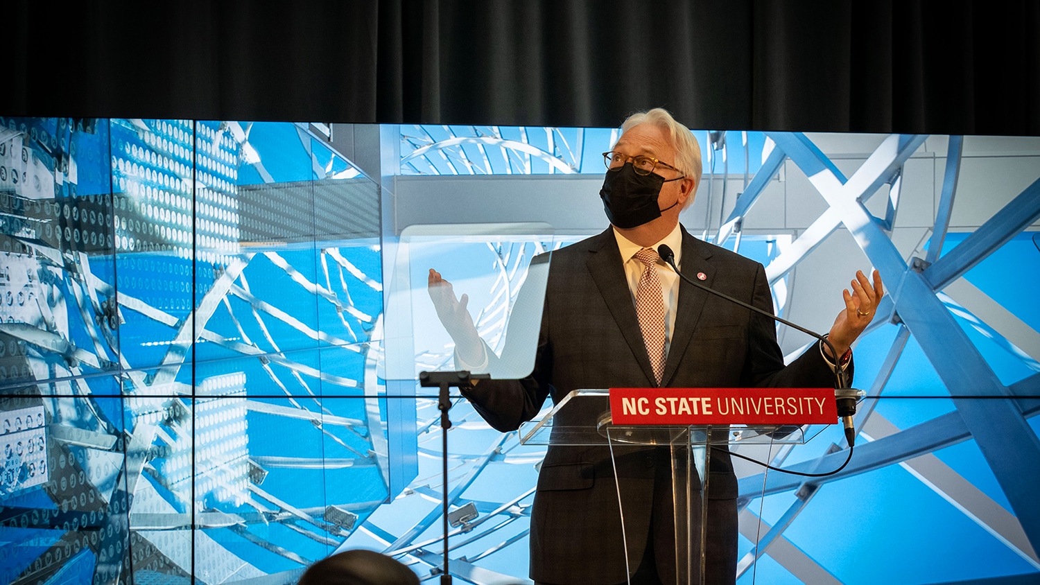 NC State Chancellor Randy Woodson standing at a podium and wearing a mask.