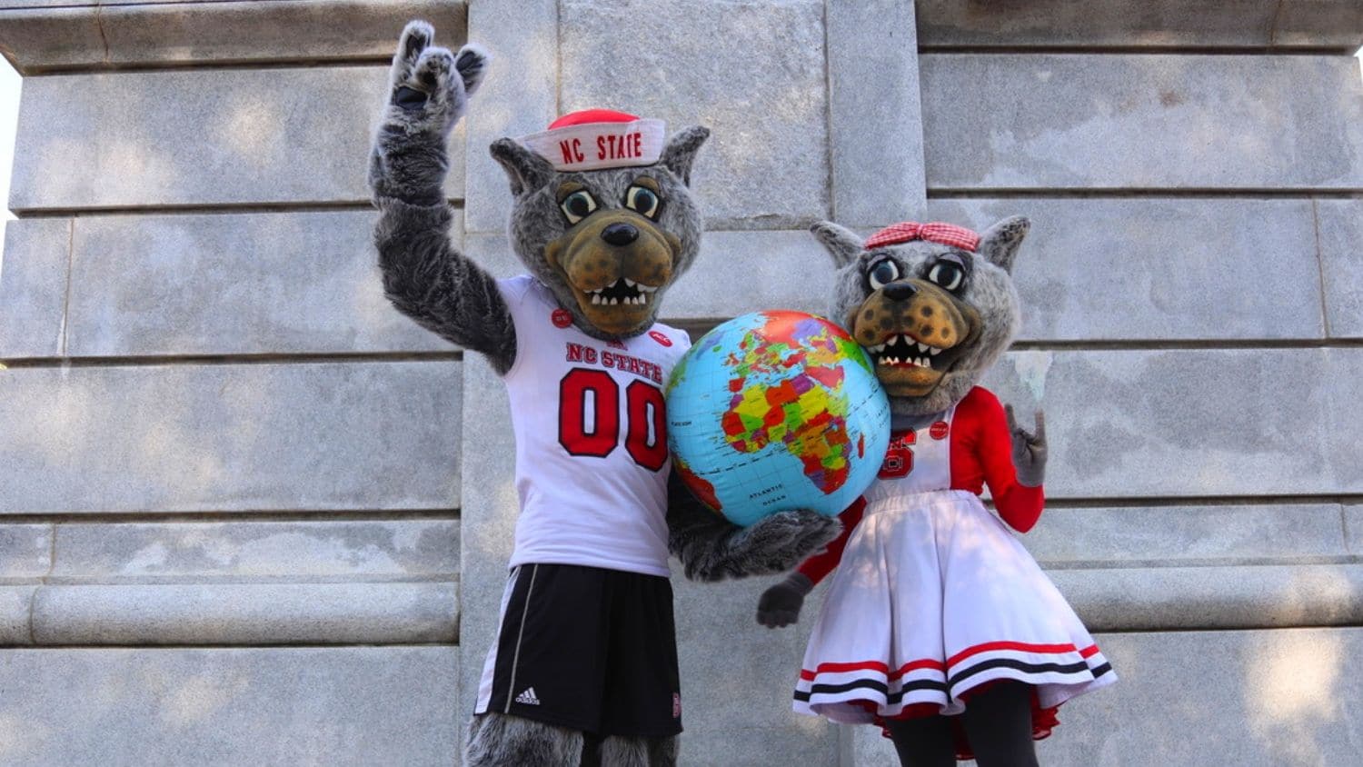 Mr. and Ms. Wuf hold a globe on campus.