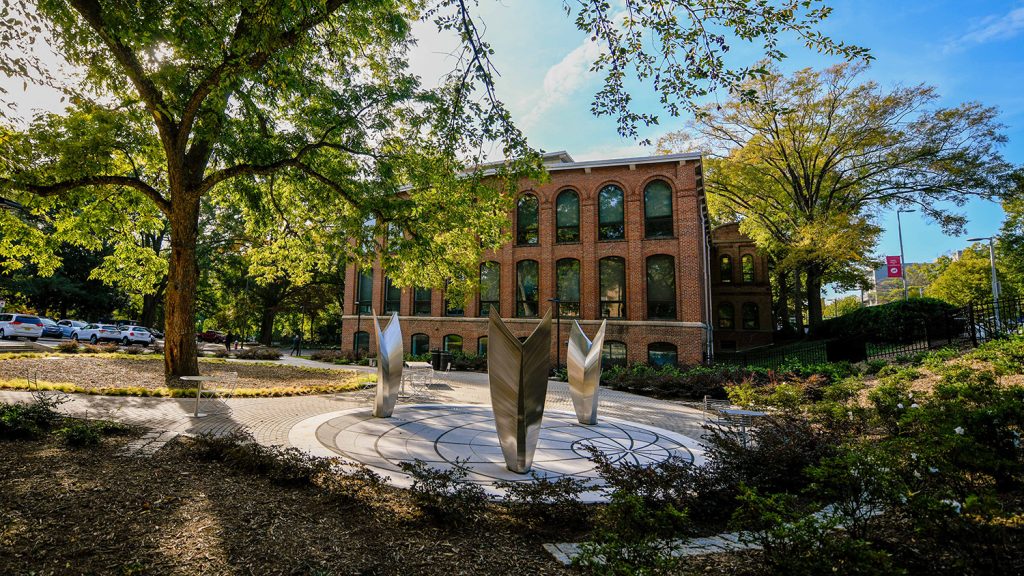 The three silver pieces of the Dream of Flight sculpture stand at the Global Courtyard on campus.