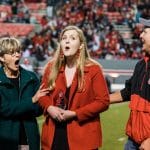 Three people with their mouths open in surprise at the Carter-Finley Stadium.