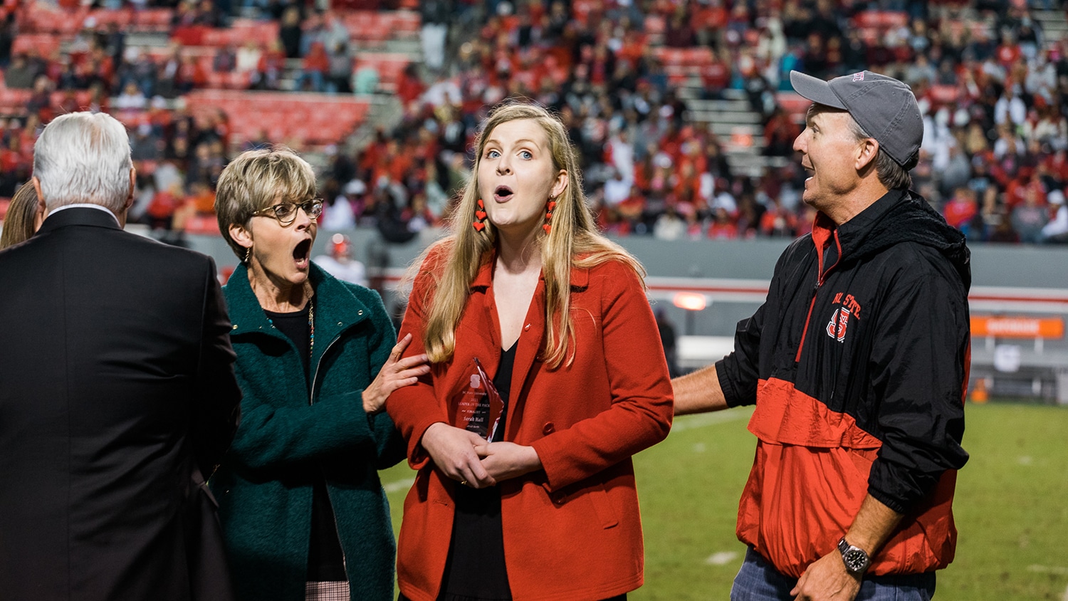Three people with their mouths open in surprise at the Carter-Finley Stadium.