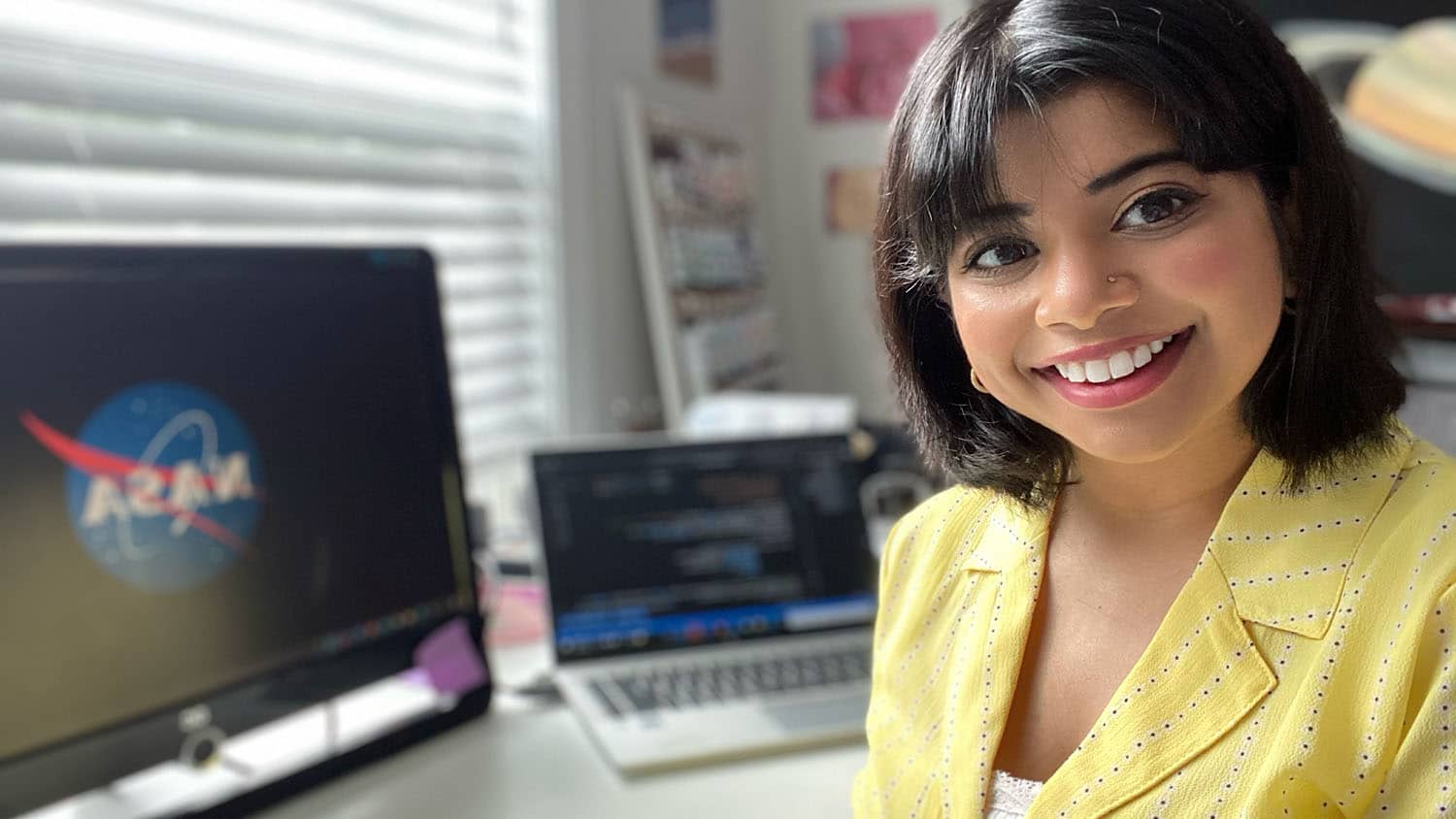 Shilpa Kancharla at her workstation with a computer screen in the background.