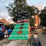 A parade float shows a cornhole board decorated to look like a football field.